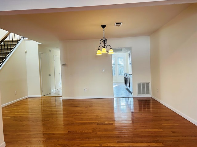 spare room featuring hardwood / wood-style floors and a chandelier