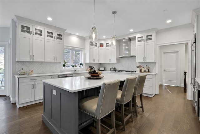 kitchen featuring white cabinets, decorative light fixtures, a center island, and wall chimney exhaust hood