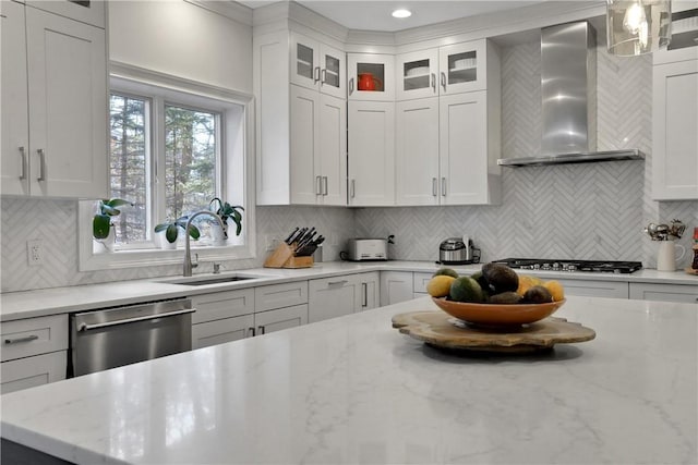 kitchen featuring hanging light fixtures, stainless steel appliances, light stone counters, white cabinets, and wall chimney exhaust hood