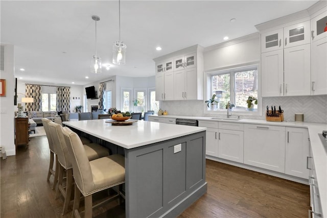 kitchen with white cabinetry, decorative light fixtures, a center island, and sink