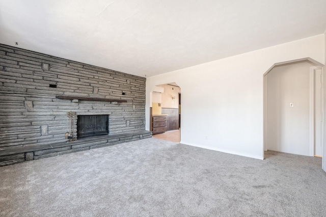 unfurnished living room featuring carpet and a stone fireplace