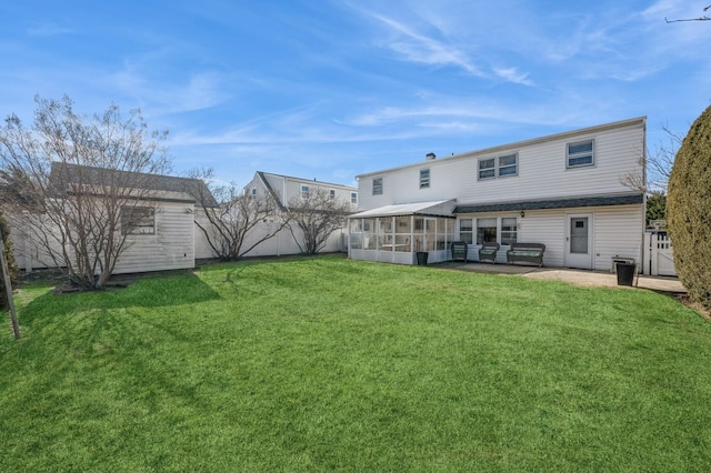 rear view of house featuring a patio, a sunroom, and a lawn