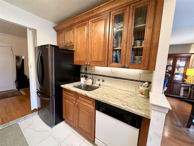 kitchen with dishwasher, sink, stainless steel fridge, backsplash, and light stone countertops