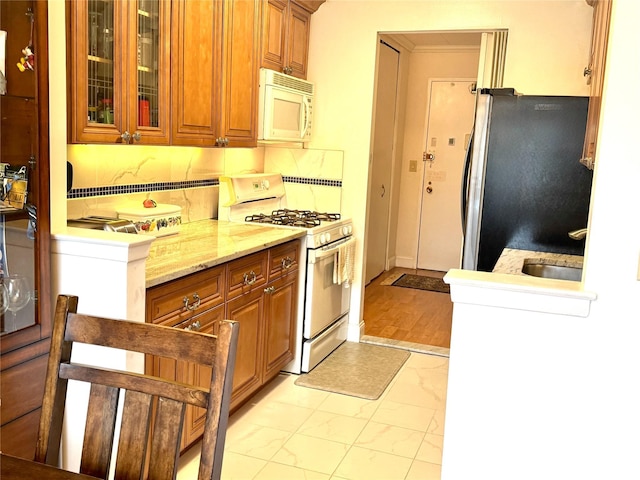 kitchen featuring ornamental molding, light stone countertops, and white appliances