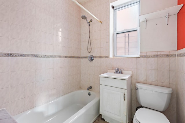 full bathroom featuring vanity, toilet, tiled shower / bath combo, and tile walls