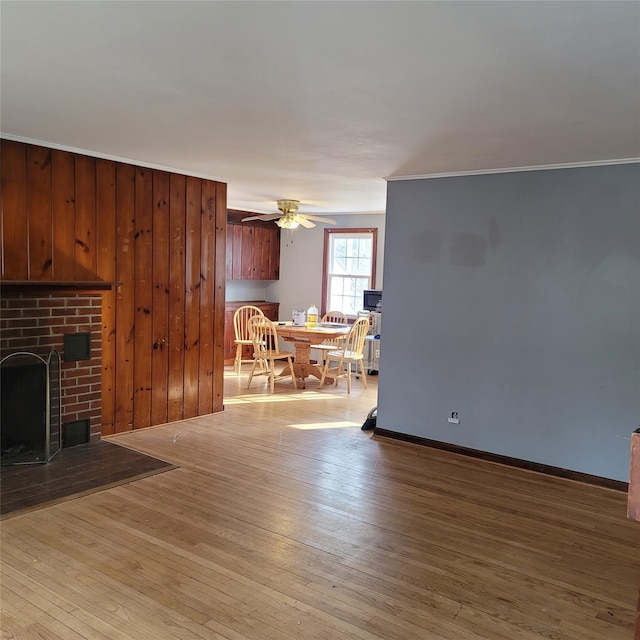 unfurnished living room with a brick fireplace, crown molding, ceiling fan, and light hardwood / wood-style flooring