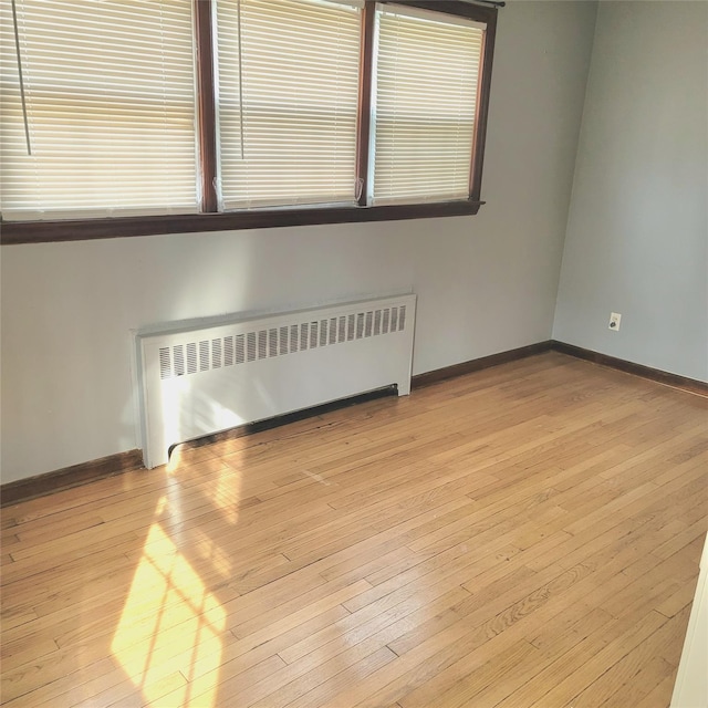 unfurnished room with radiator heating unit and light hardwood / wood-style flooring