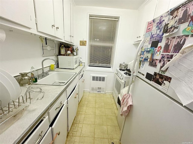 kitchen with sink, white appliances, radiator heating unit, and white cabinets