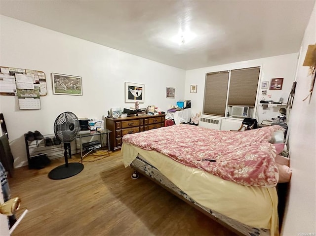 bedroom featuring radiator heating unit, hardwood / wood-style floors, and cooling unit