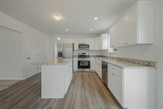 kitchen with light stone countertops, a center island, white cabinets, and appliances with stainless steel finishes