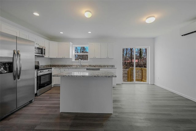 kitchen featuring appliances with stainless steel finishes, sink, white cabinets, a center island, and light stone counters