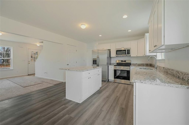 kitchen featuring a kitchen island, white cabinetry, sink, stainless steel appliances, and light hardwood / wood-style flooring