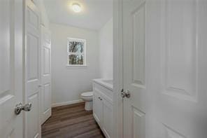 bathroom with hardwood / wood-style flooring, vanity, and toilet