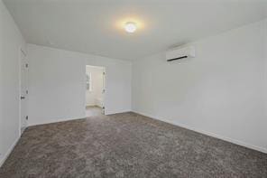 spare room featuring a wall mounted AC and carpet