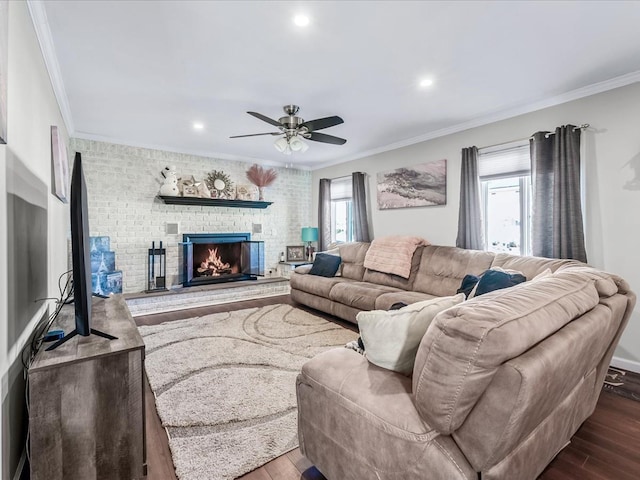 living room featuring hardwood / wood-style flooring, ceiling fan, ornamental molding, and a brick fireplace