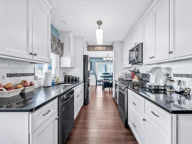 kitchen with pendant lighting, sink, appliances with stainless steel finishes, white cabinetry, and dark hardwood / wood-style floors