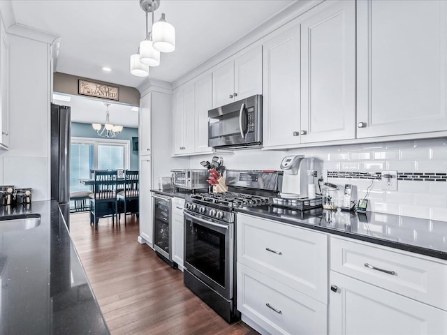 kitchen featuring appliances with stainless steel finishes, white cabinets, beverage cooler, hanging light fixtures, and an inviting chandelier