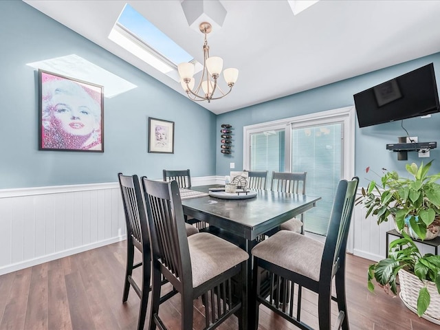 dining area featuring hardwood / wood-style floors, a notable chandelier, and vaulted ceiling with skylight