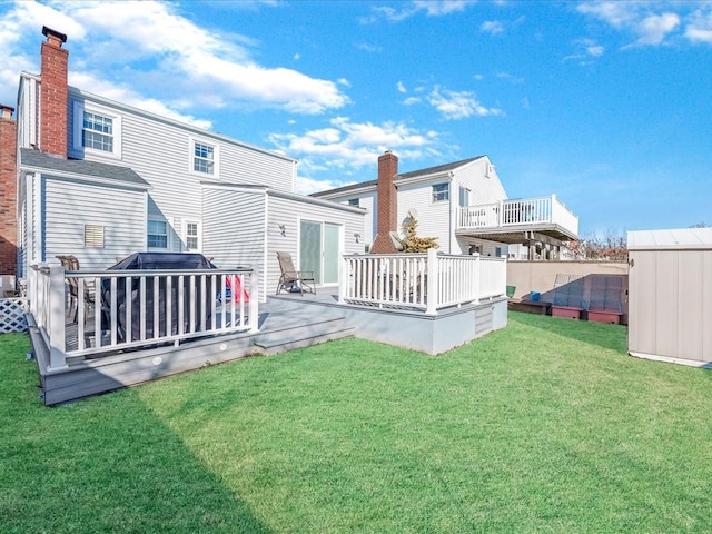 back of property with a storage shed, a lawn, and a deck