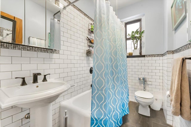 full bathroom featuring sink, tile walls, tile patterned floors, toilet, and shower / bath combo with shower curtain