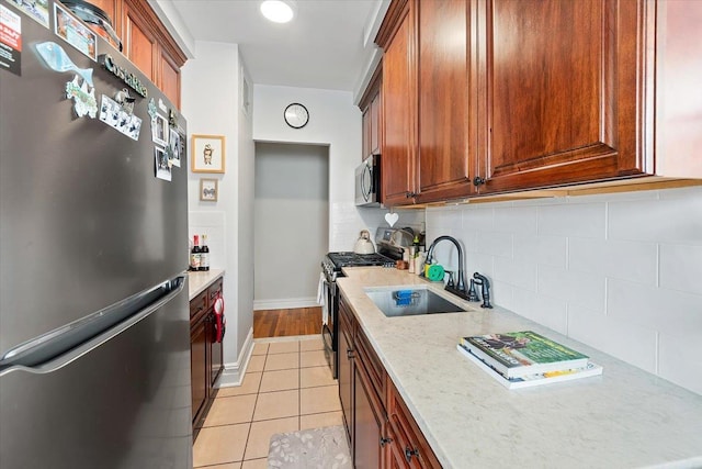 kitchen with sink, tasteful backsplash, light tile patterned floors, stainless steel appliances, and light stone countertops