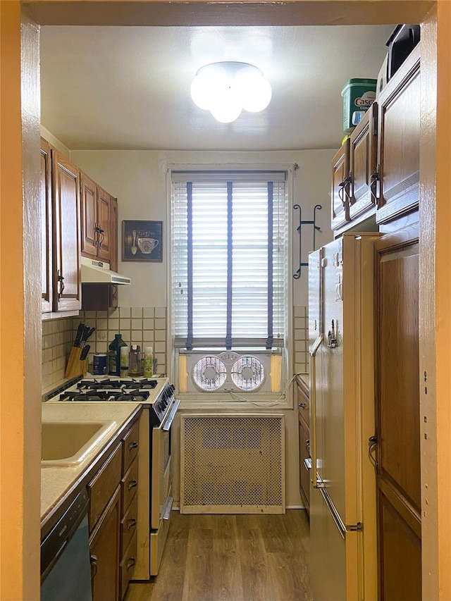 kitchen featuring dark wood-type flooring, gas range, refrigerator, radiator, and dishwasher