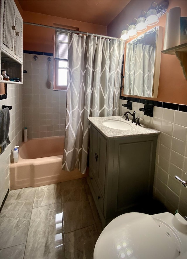 full bathroom featuring tile patterned floors, toilet, tile walls, vanity, and shower / bath combo with shower curtain