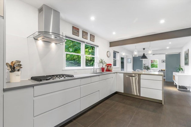 kitchen with a peninsula, a sink, stainless steel appliances, white cabinets, and wall chimney range hood