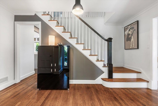 staircase featuring visible vents, crown molding, baseboards, and wood finished floors