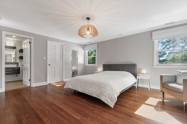 bedroom featuring a sink, visible vents, baseboards, and wood finished floors