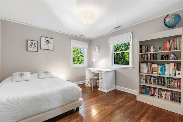 bedroom with visible vents, crown molding, baseboards, and wood finished floors