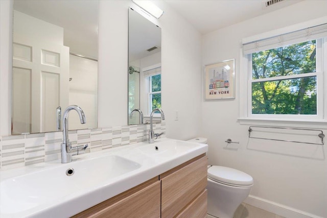 bathroom featuring toilet, visible vents, backsplash, and a sink