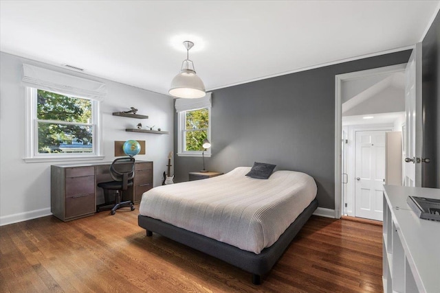 bedroom with dark wood-style floors, visible vents, and baseboards