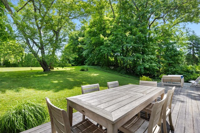 wooden deck with outdoor dining area and a lawn