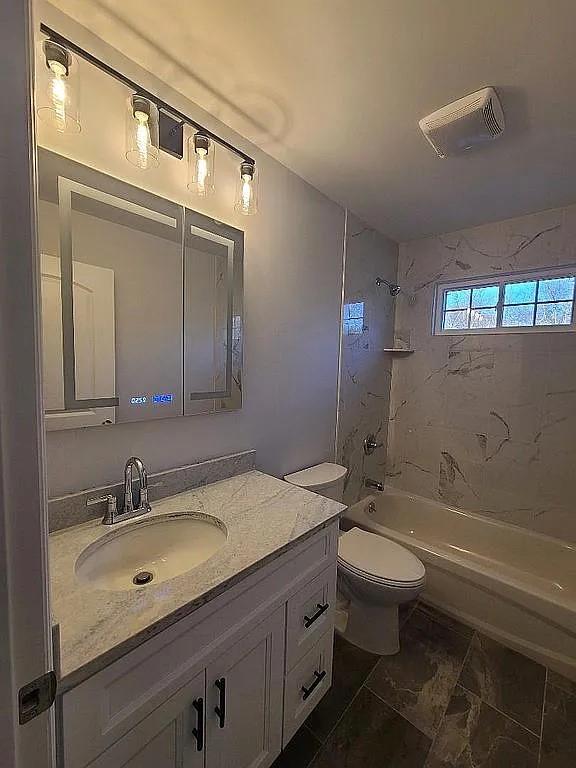 full bathroom with vanity, toilet, and tiled shower / bath