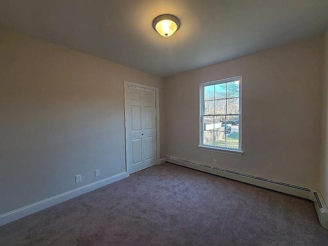 empty room featuring a baseboard heating unit and carpet floors