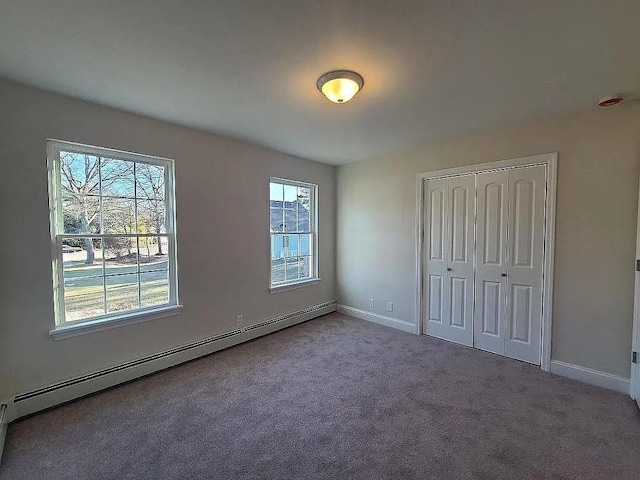 unfurnished bedroom featuring carpet, a baseboard heating unit, and a closet