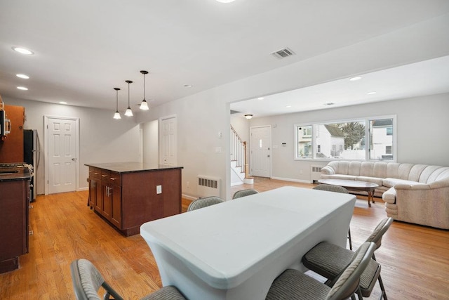 dining space with radiator and light wood-type flooring