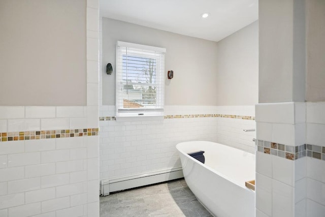 bathroom featuring baseboard heating, tile walls, and a tub