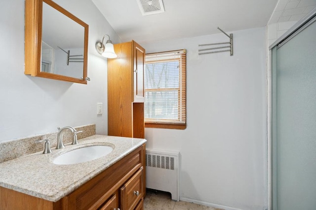 bathroom with vanity, radiator, and a shower with shower door