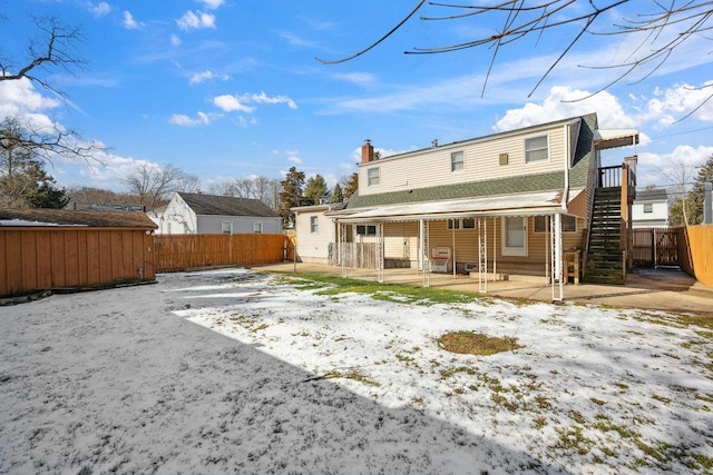 snow covered back of property featuring a patio