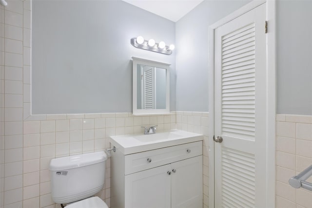 bathroom with vanity, toilet, and tile walls