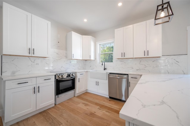 kitchen featuring range, light stone counters, white cabinets, decorative light fixtures, and stainless steel dishwasher