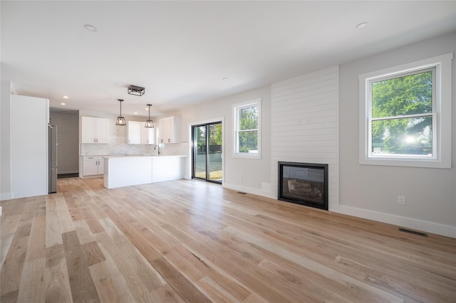 unfurnished living room with a large fireplace and light wood-type flooring