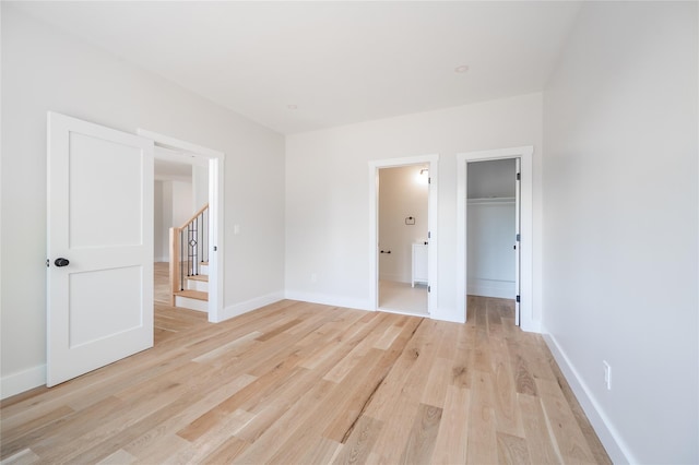 unfurnished bedroom featuring a spacious closet, a closet, and light wood-type flooring