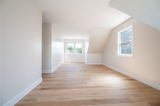 additional living space featuring vaulted ceiling and light wood-type flooring