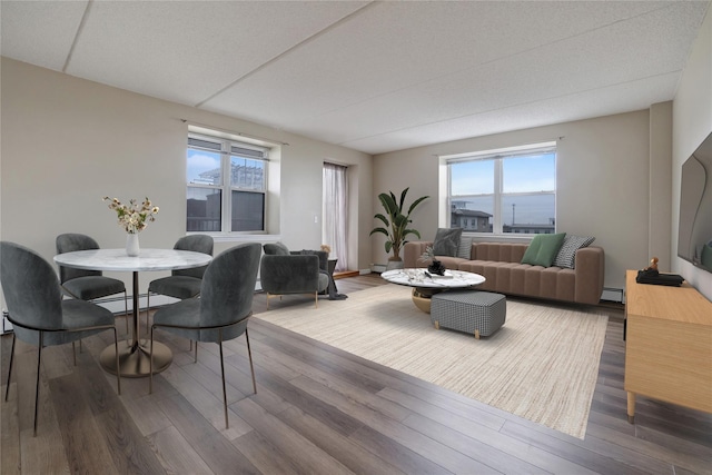 dining area with hardwood / wood-style flooring, a healthy amount of sunlight, and a baseboard heating unit