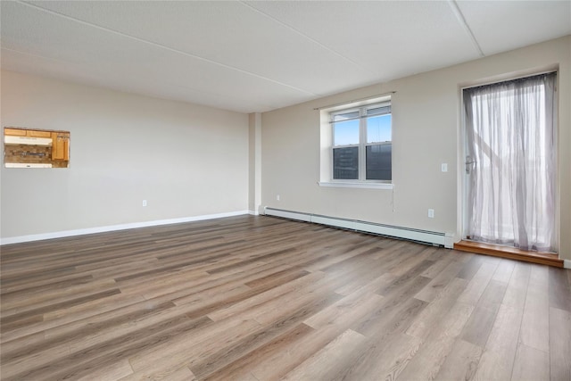 unfurnished room featuring plenty of natural light, light wood-type flooring, and baseboard heating