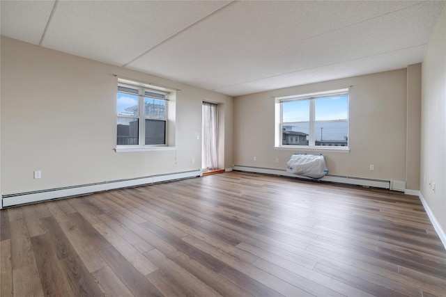 empty room with hardwood / wood-style flooring and a baseboard radiator