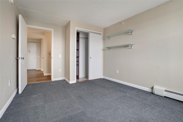 unfurnished bedroom with a closet, dark carpet, and baseboard heating